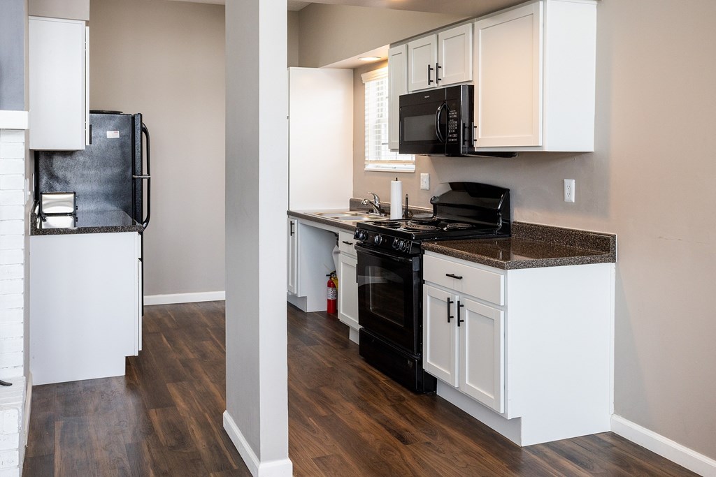 A kitchen with black appliances and white cabinets.