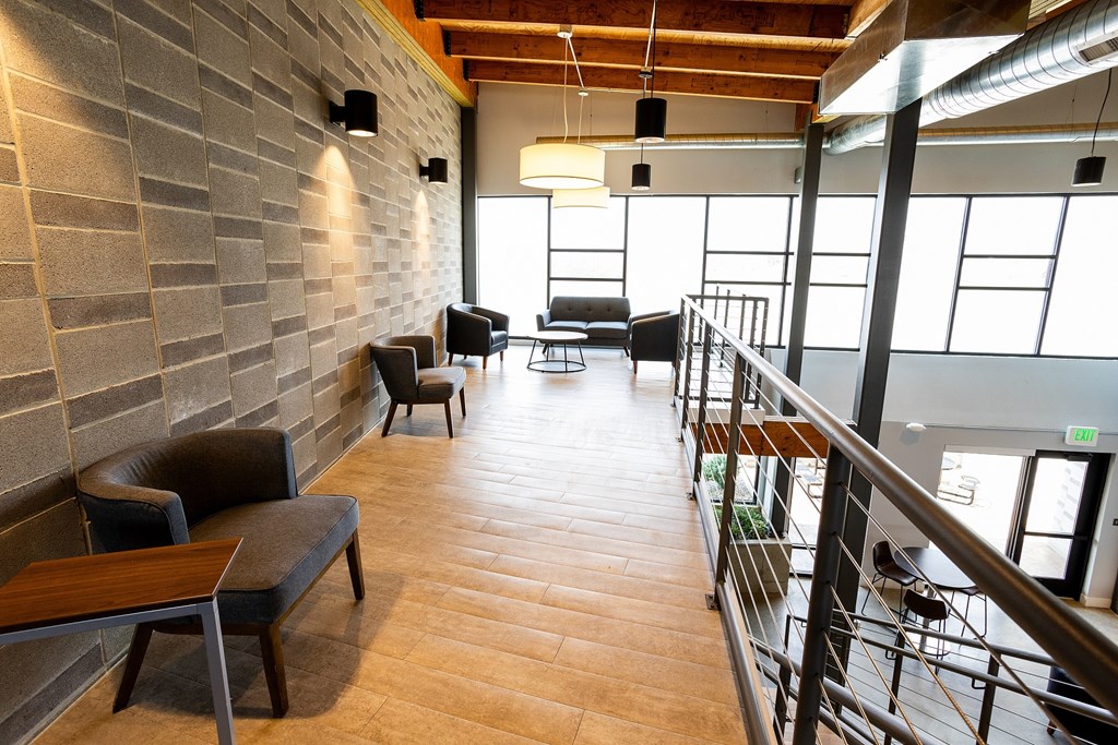 A long hallway with a couch and chairs on the left and a railing on the right.
