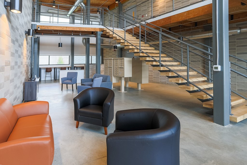 A modern interior with a staircase and leather chairs.