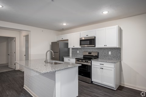 A kitchen with white cabinets and a granite countertop.