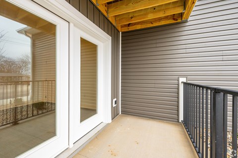 A patio with a sliding glass door and a black railing.