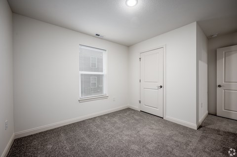 Bedroom with a carpeted floor, a window with blinds, and walk-in closet