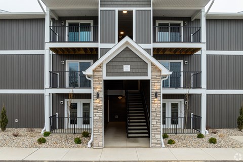 A modern two-story apartment building with a front entrance and a balcony.