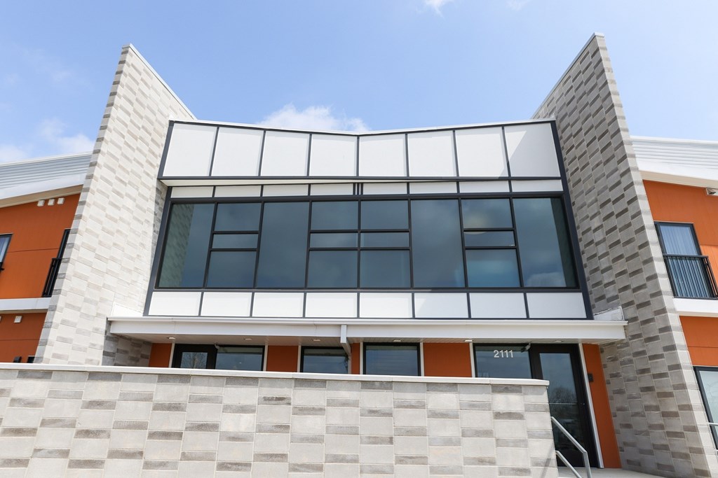 A modern building with a white and orange facade and a large glass window.
