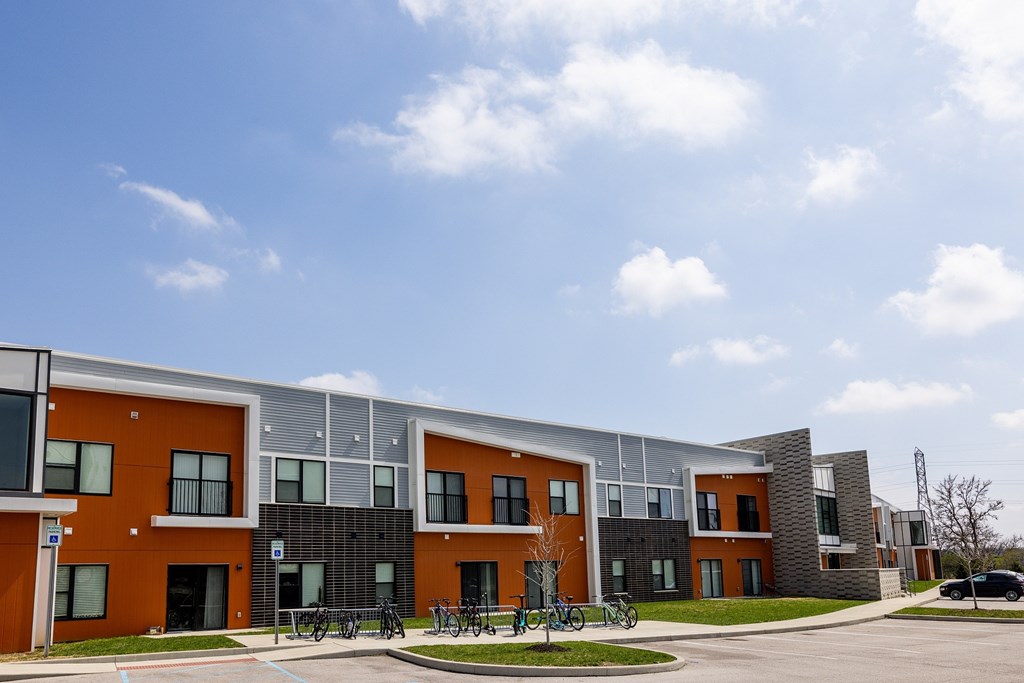A modern building with orange and grey exterior and a clear blue sky above.