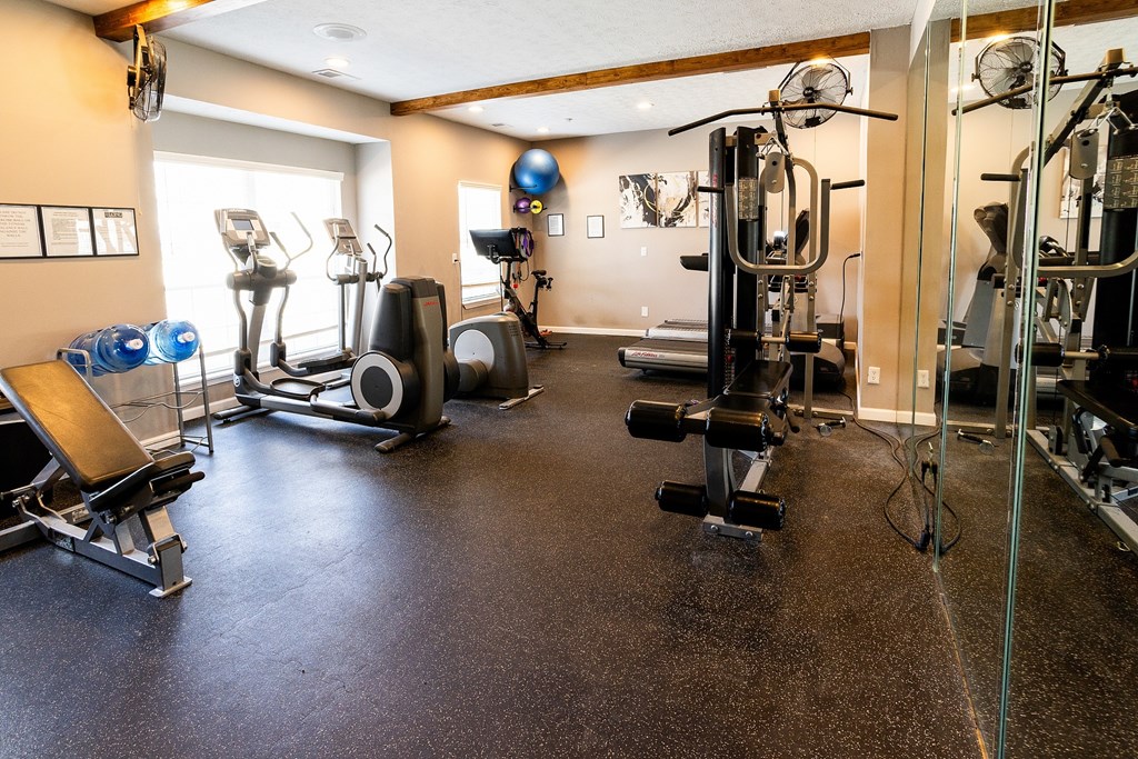 A spacious gym with a variety of equipment including a treadmill, weights, and a bench press.