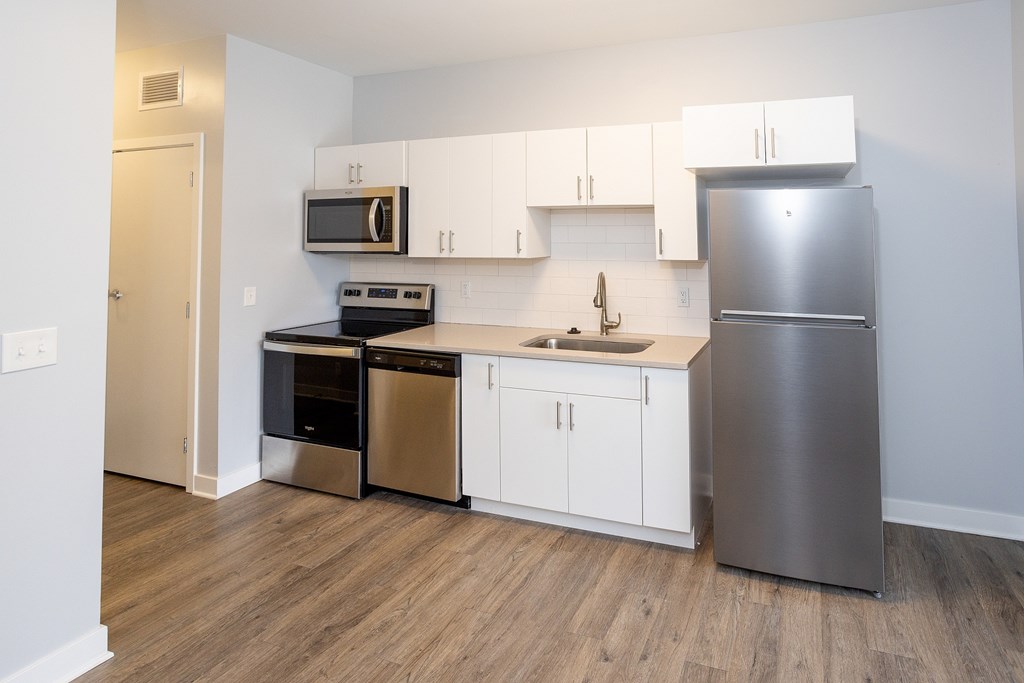 A kitchen with a stainless steel refrigerator, microwave, oven, and sink.