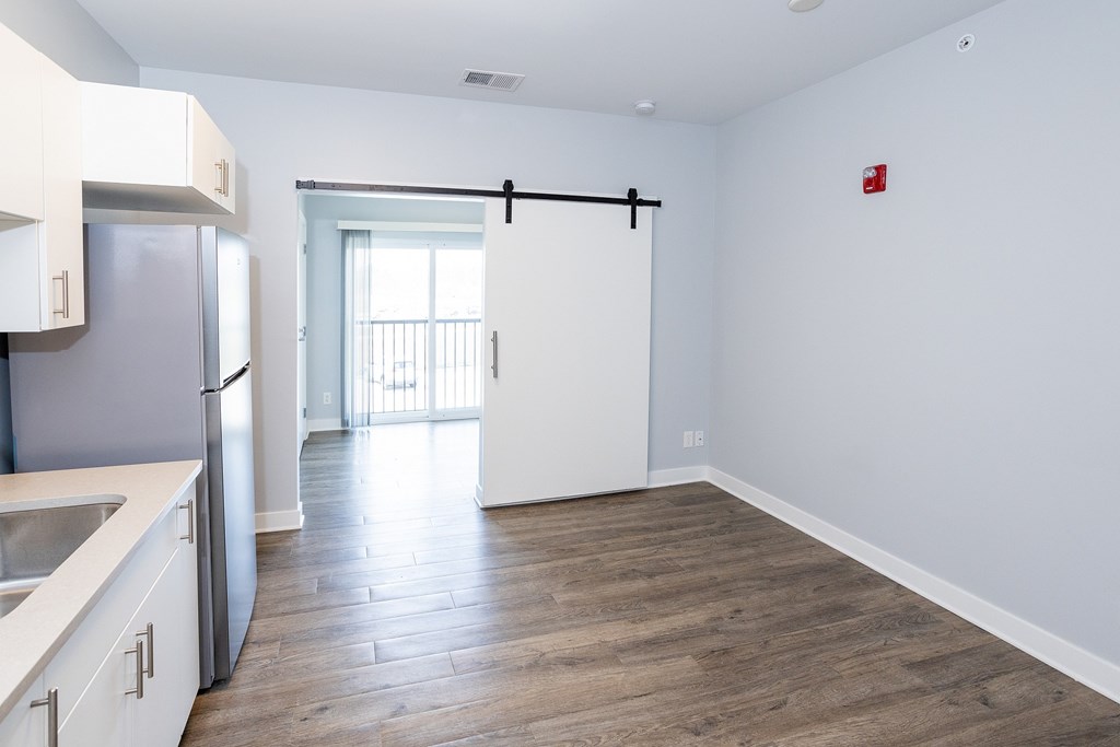 A kitchen with white cabinets and a wooden floor.
