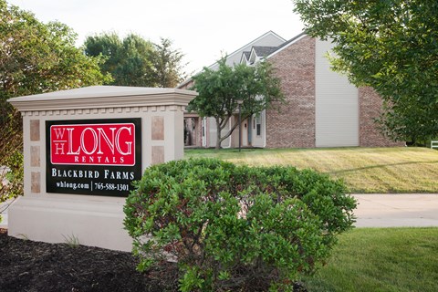 A sign for Long Blackbird Farms is in front of a building.