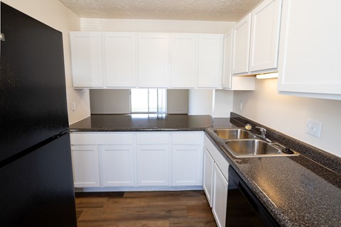 A kitchen with black fridge and white cabinets.