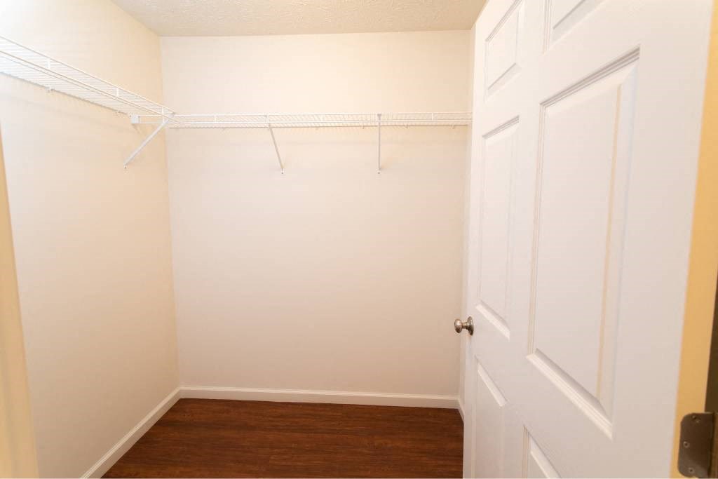 A white door is on the right side of a room with a white wall and a white closet rod.