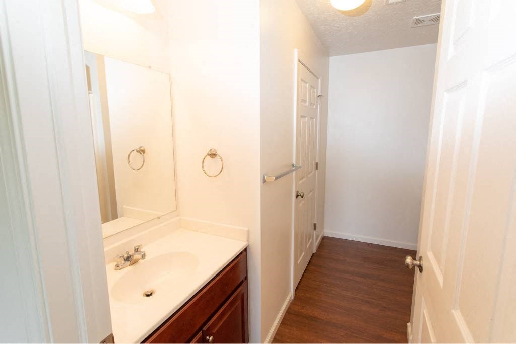 A white bathroom with a wooden floor and a white sink.