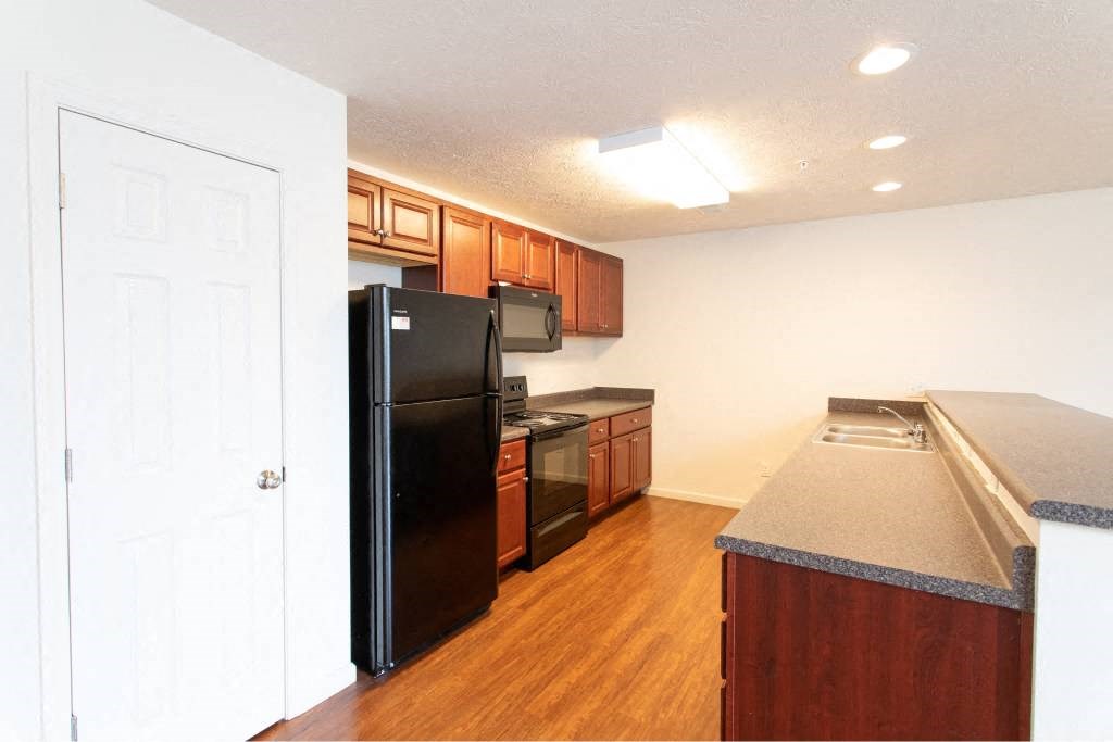 A kitchen with black appliances and wooden cabinets.