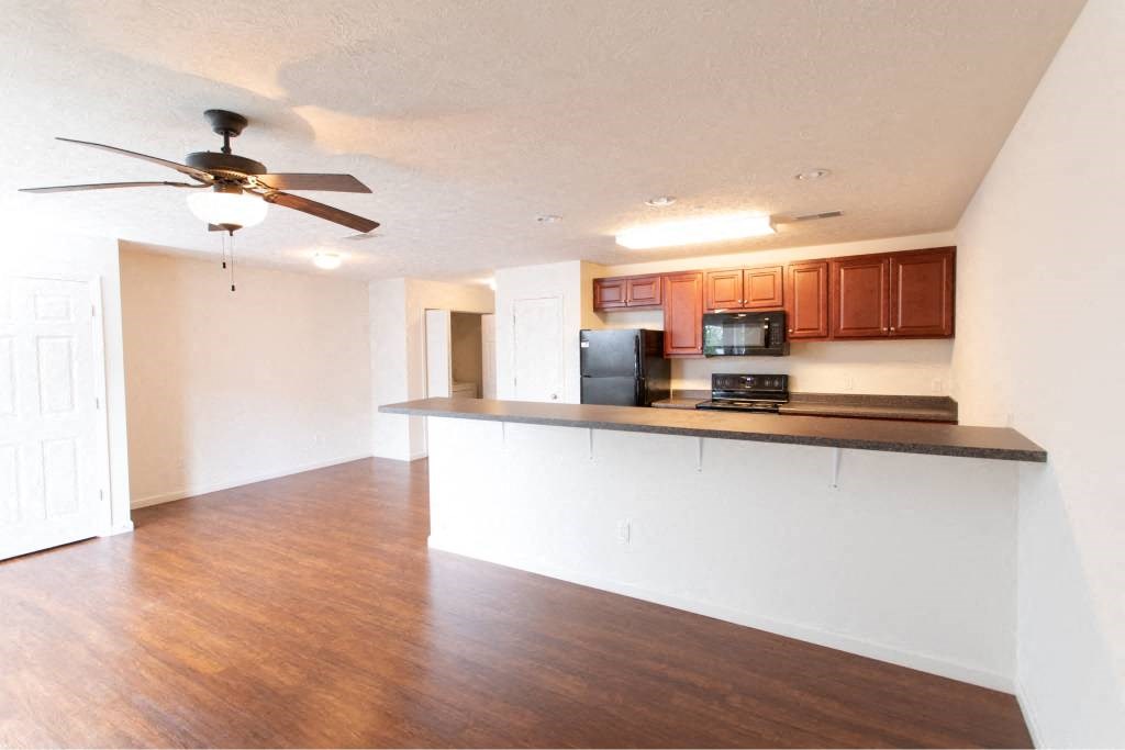 A kitchen with a refrigerator, microwave, and oven.