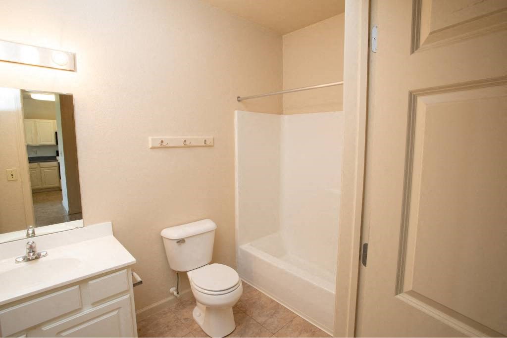A white toilet sits in a bathroom next to a sink and a shower.