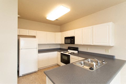 A kitchen with white cabinets and a black stove top oven.