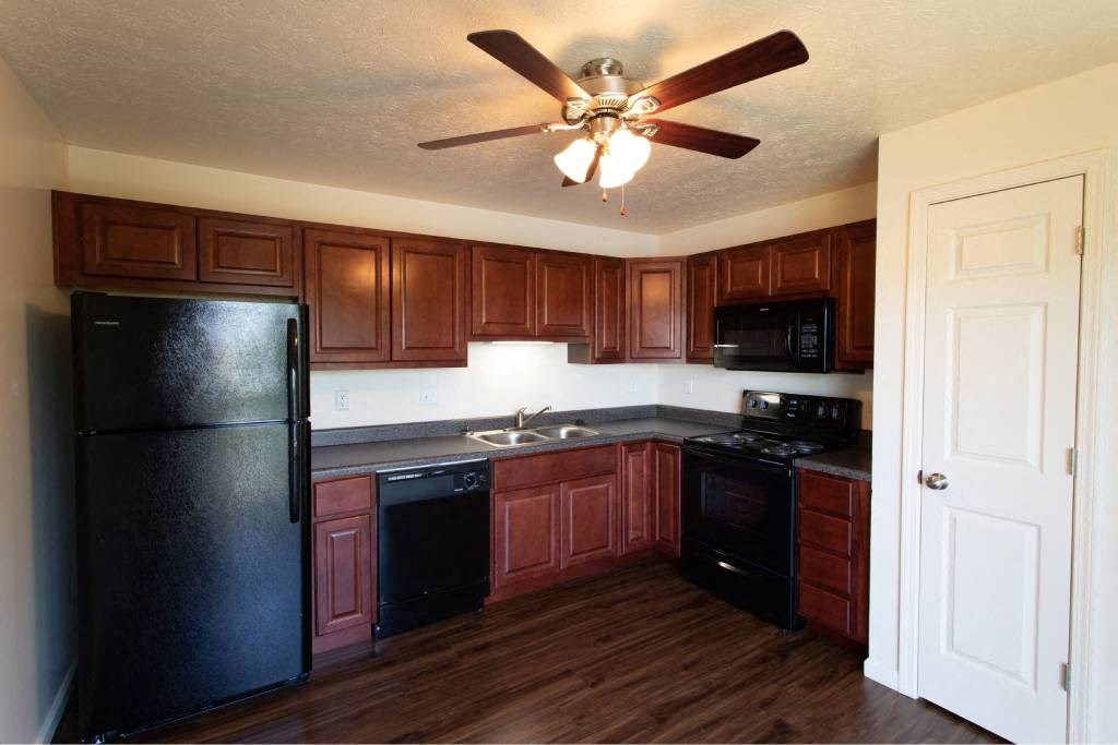 A kitchen with wooden cabinets and a black refrigerator.