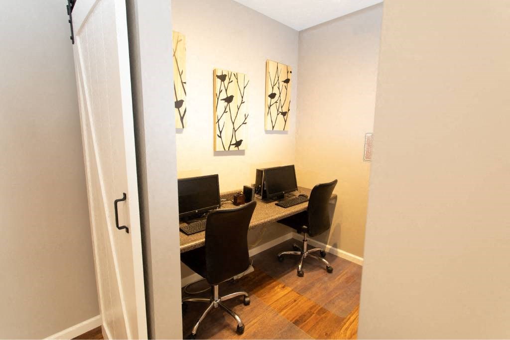 A room with a desk and chairs and a clock on the wall.