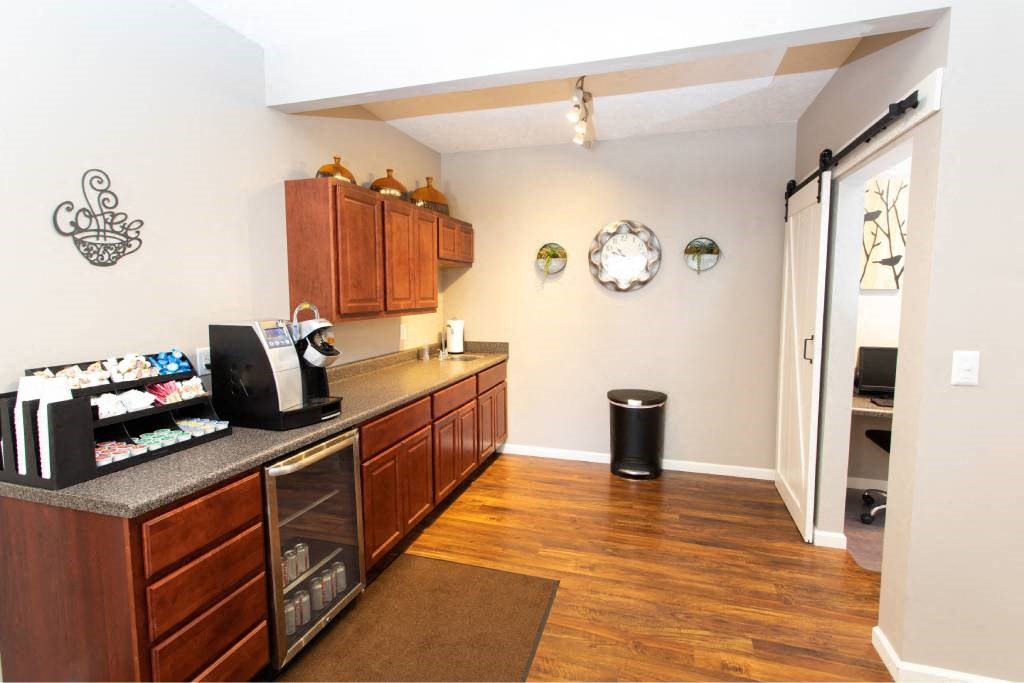 A kitchen with wooden cabinets and a black trash can.