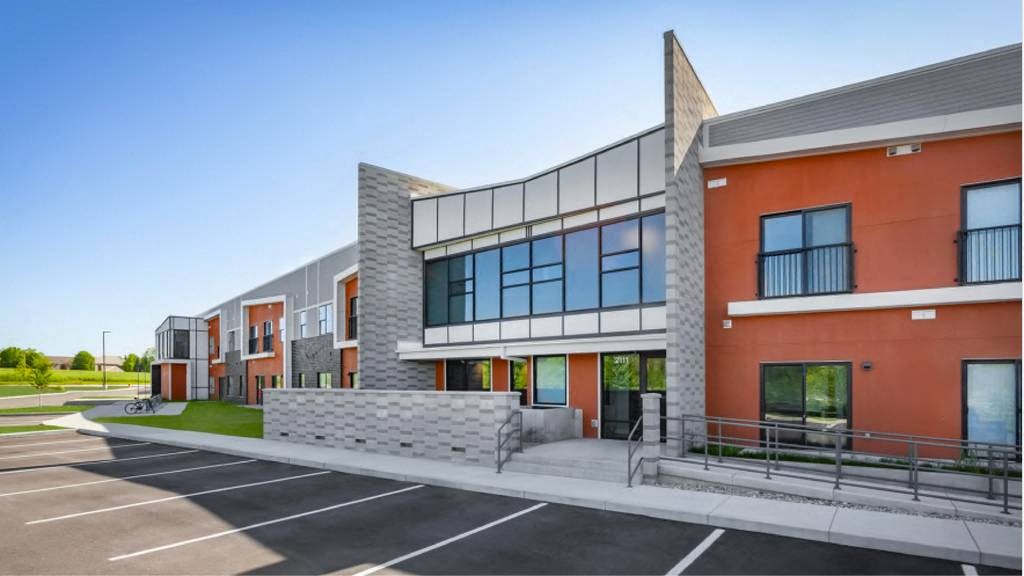 A modern building with a parking lot in front.