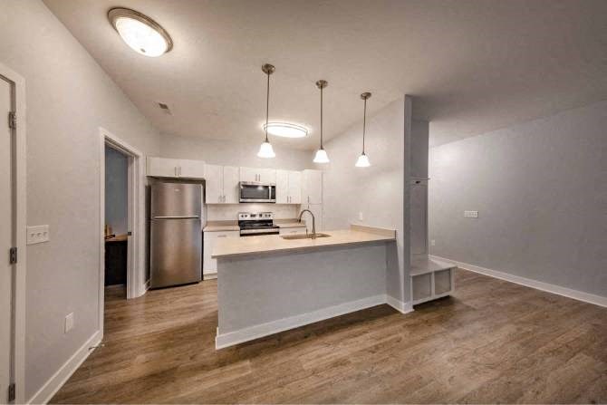 A kitchen with a stainless steel refrigerator, a microwave, and a countertop with a sink.