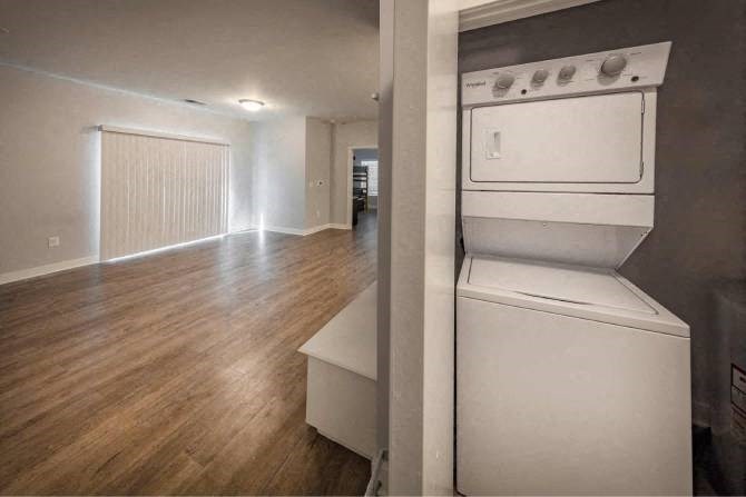 A white dryer is in a room with wood flooring.