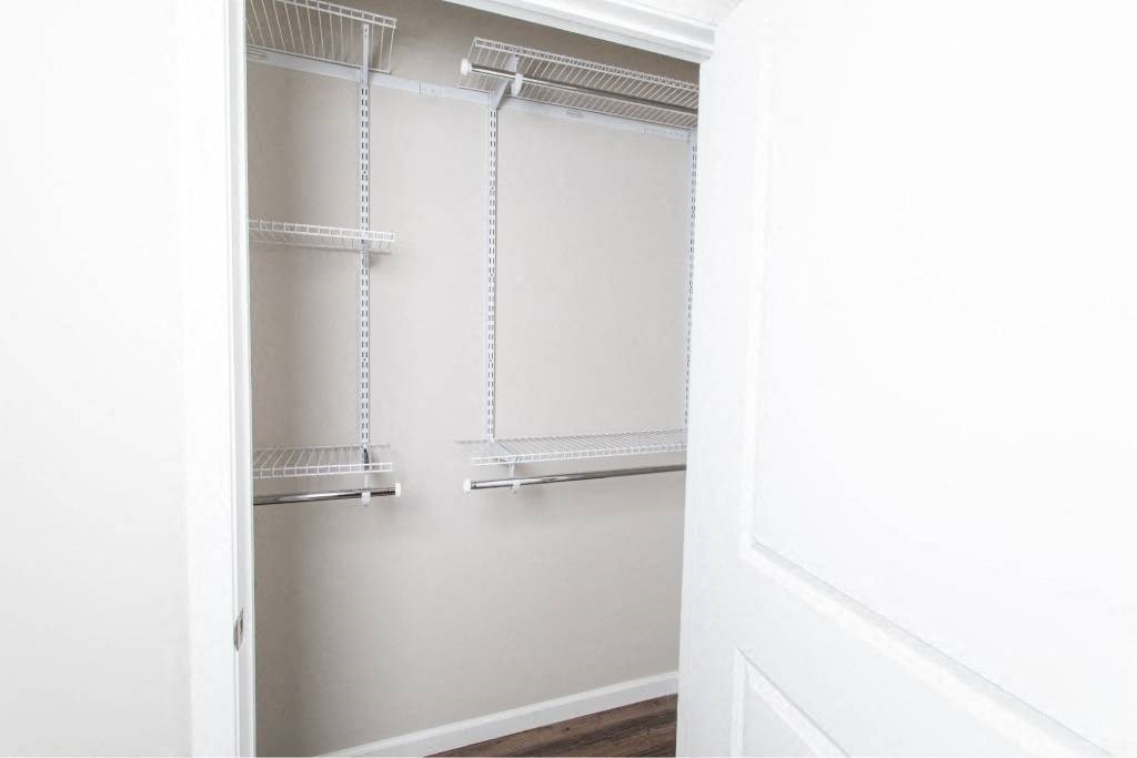 A white door is open to reveal a white pantry with three shelves.