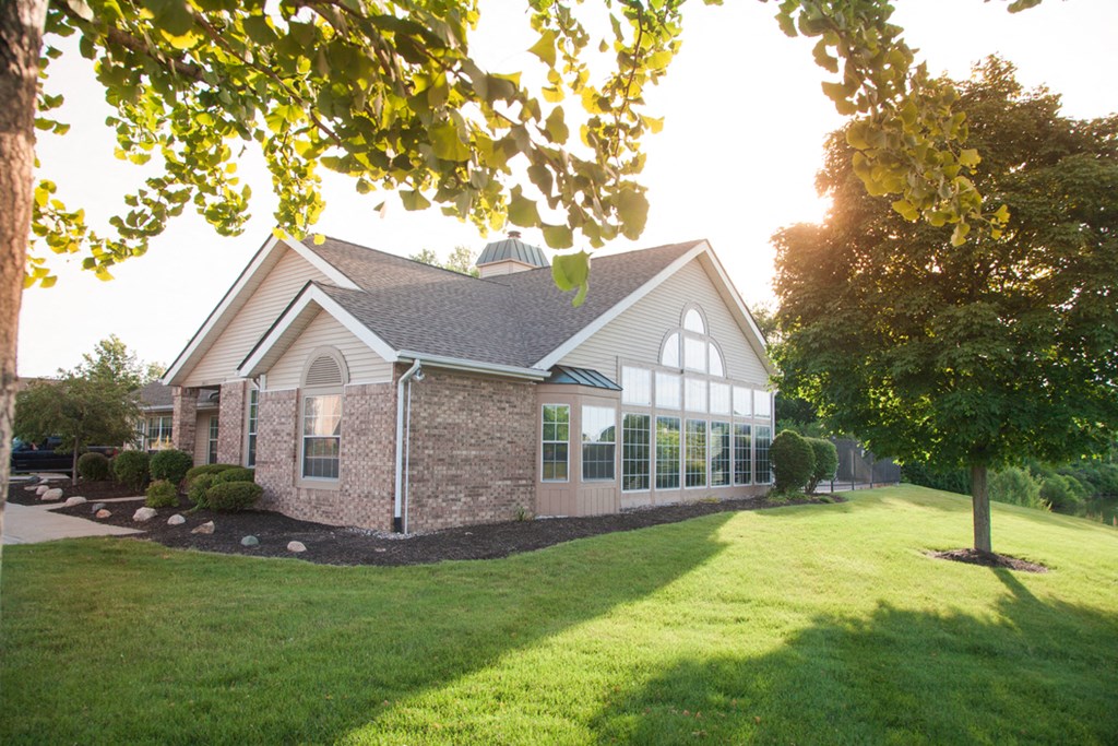 A house with a green lawn and trees in the background.