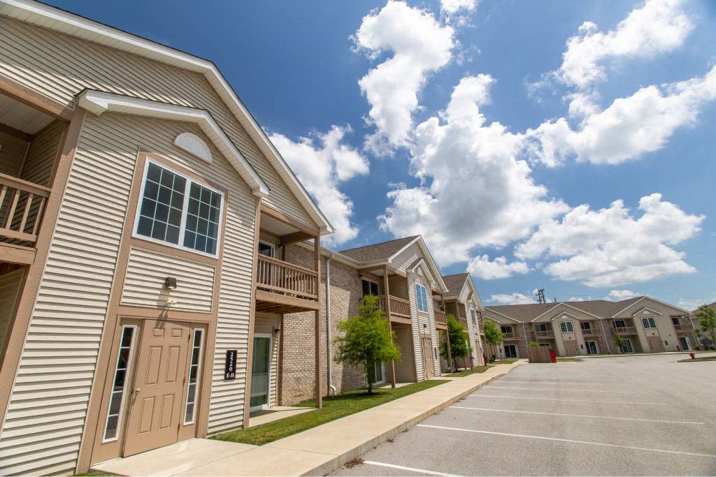 A row of apartment buildings with a parking lot in front.
