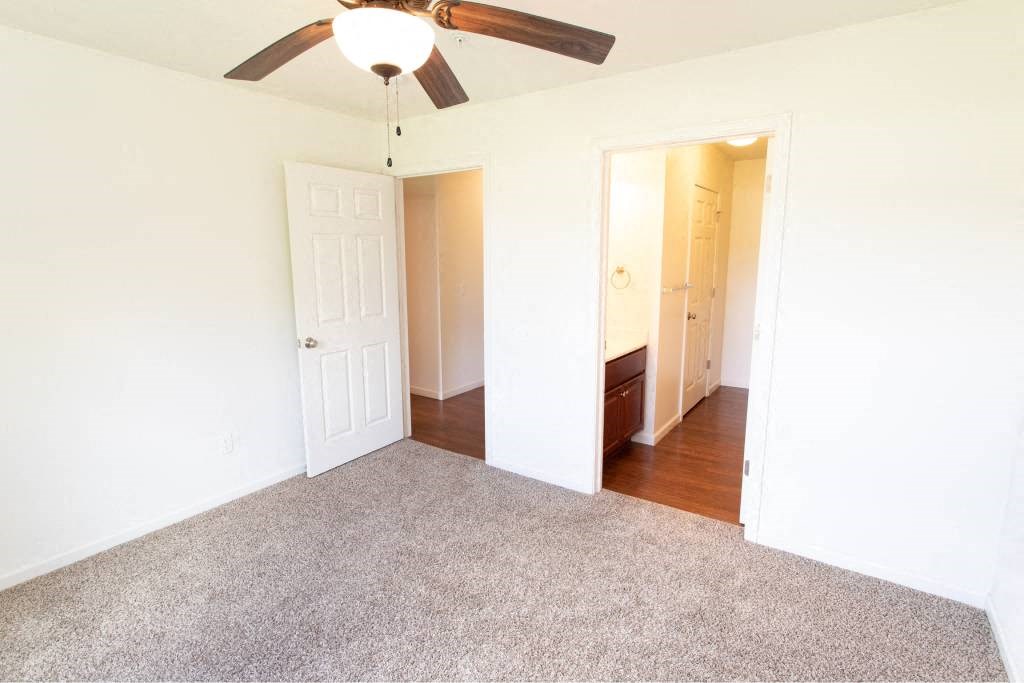 A room with a ceiling fan and carpeted floor.