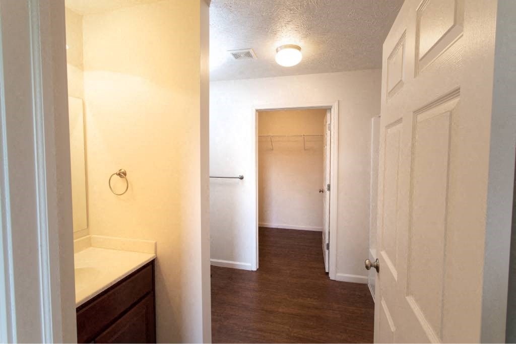 A white bathroom with a wooden vanity and a white door.