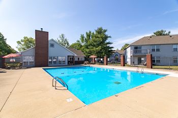 A small pool in a backyard with a house in the background.