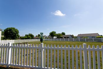 A white picket fence in front of a green sign and houses.