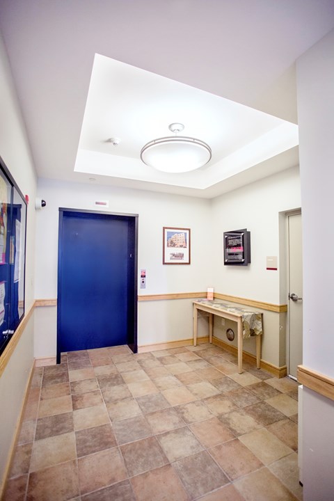 A hallway with a blue door and a bench.