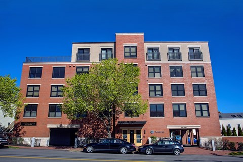 A red brick building with a tree in front of it.