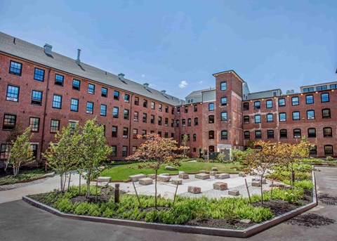A courtyard with a garden in front of a red brick building.