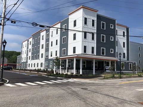 A street view of a multi-story building with a crosswalk in front.