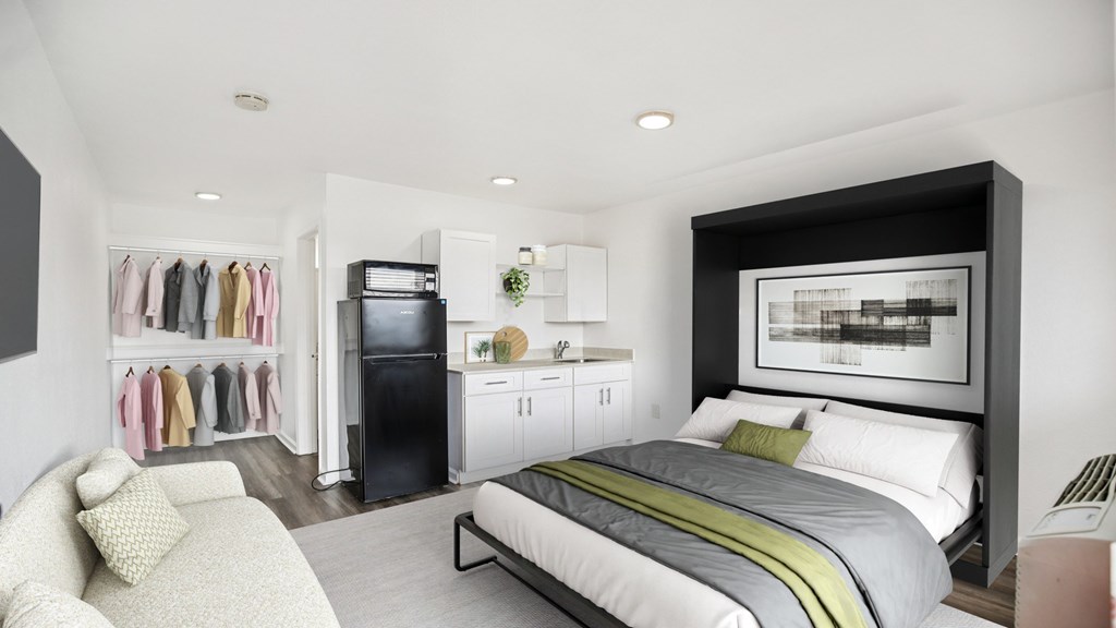 A modern bedroom with a large bed and a wardrobe with clothes hanging.