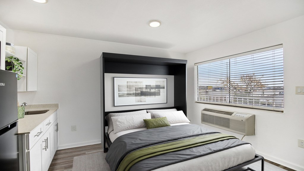 A bedroom with a large bed and a kitchen area.