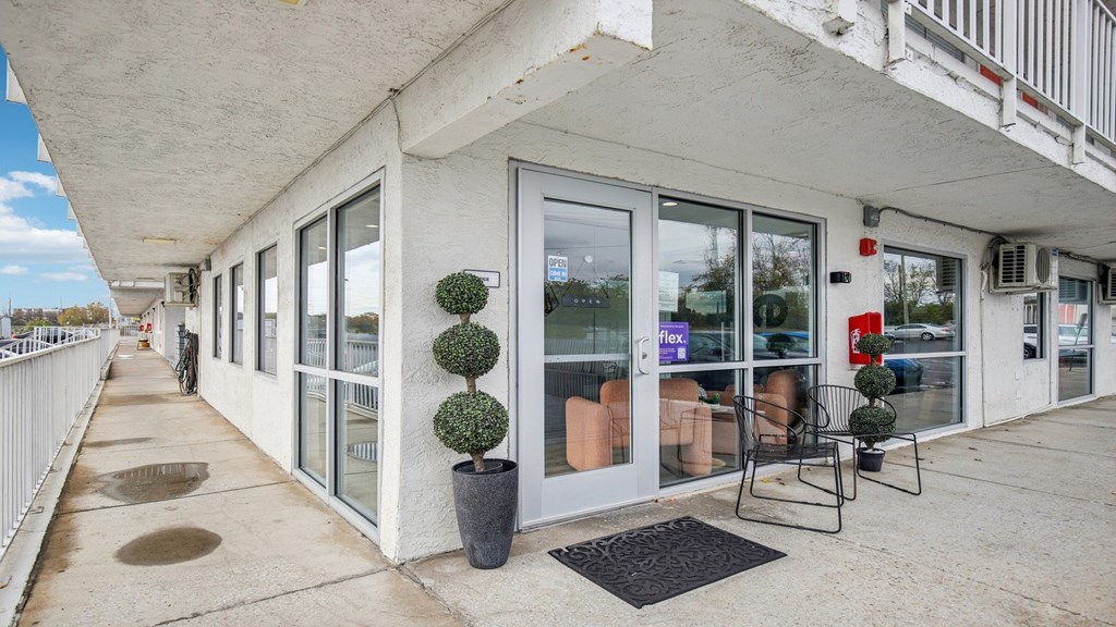 A white building with a balcony has a black mat on the floor.