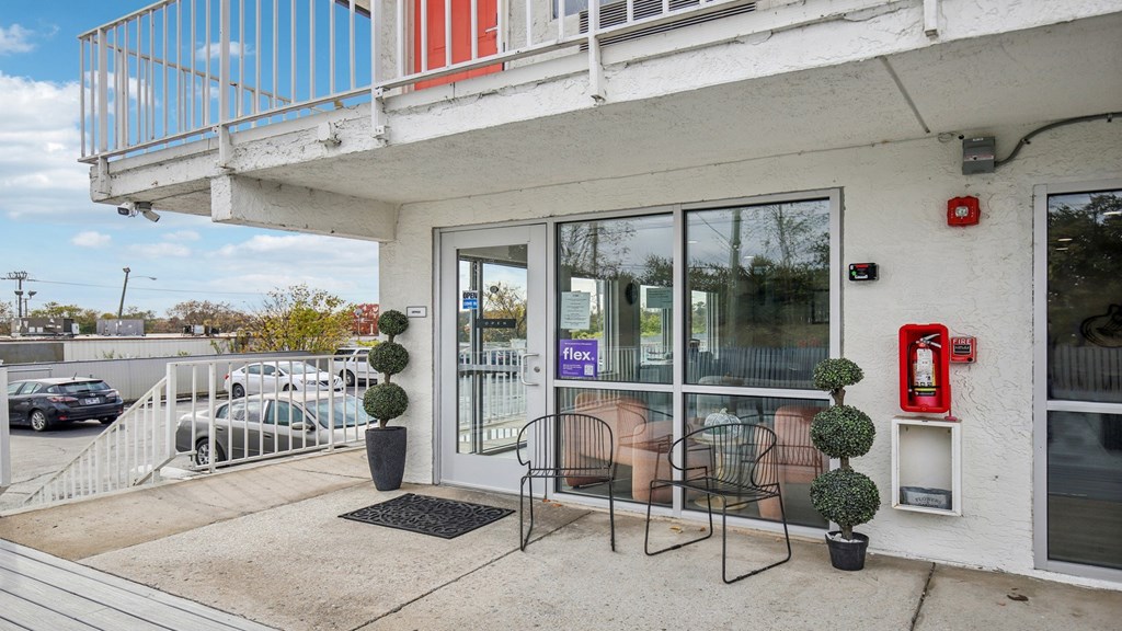 A white building with a red fire extinguisher on the wall.