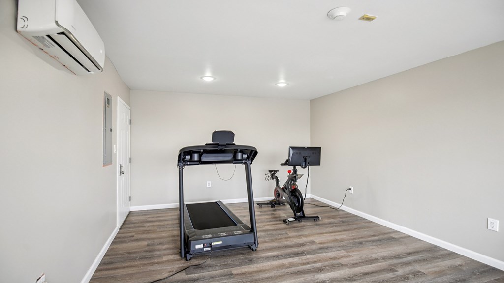 A treadmill is in the middle of a room with a wooden floor.