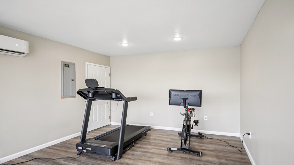 A treadmill and a stationary bike are in a room with a television.