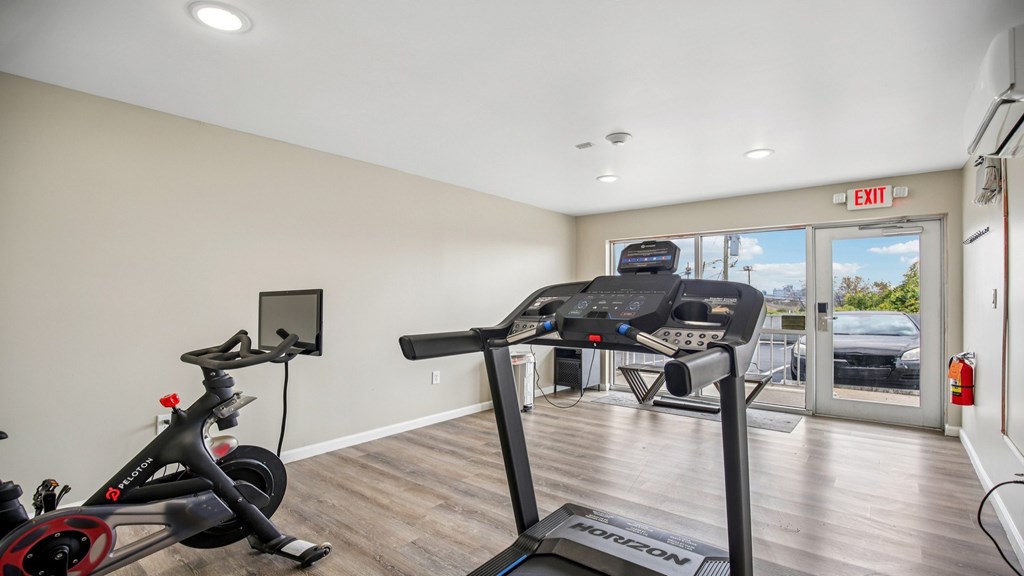 A treadmill and a stationary bike are in a room with a window.