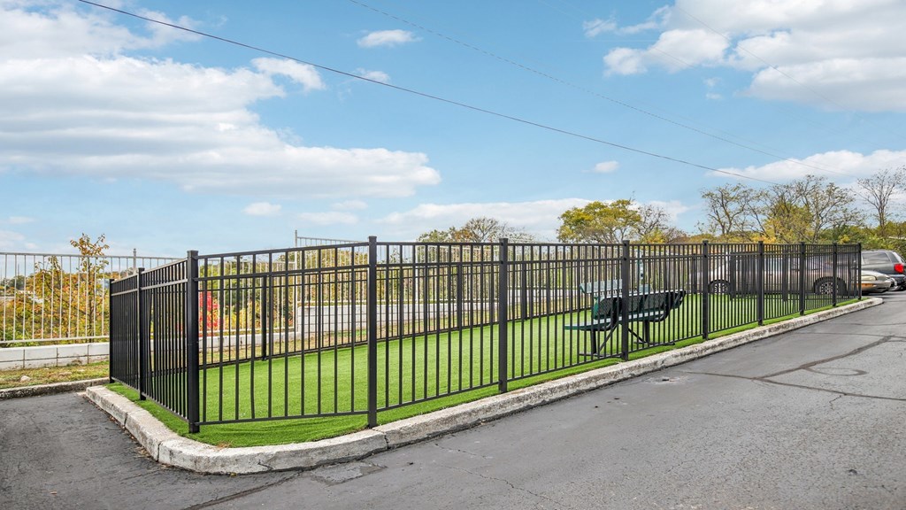 A black metal fence surrounds a green area.