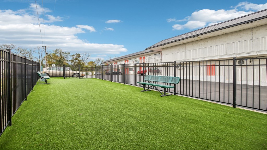 A green lawn in front of a building with a black fence.