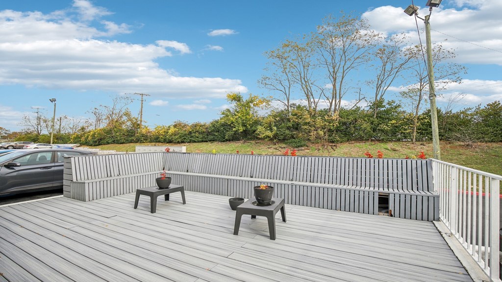 A wooden deck with two benches and a table.