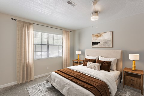 A bedroom with a large bed, a nightstand, and a window with curtains.