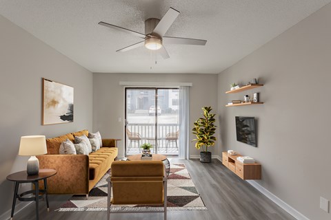 A living room with a yellow couch and a ceiling fan.