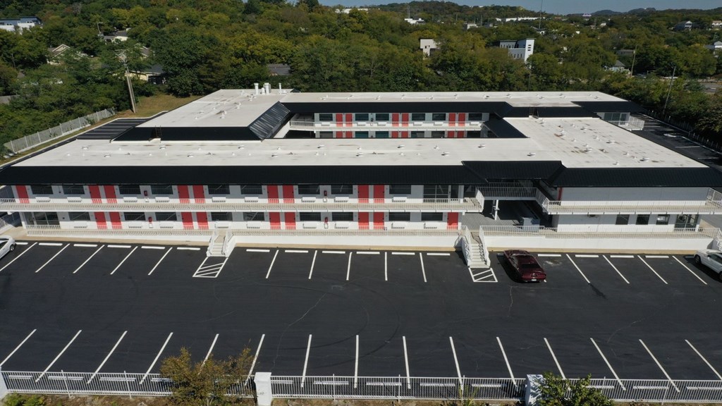 A parking lot in front of a building with a car parked in it.